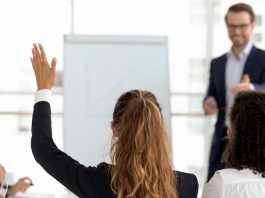 Eine Frau hebt initiativ ihre Hand.