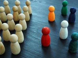 Viele gleiche, einfarbige Figuren stehen geordnet einzelnen bunten Figuren gegenüber