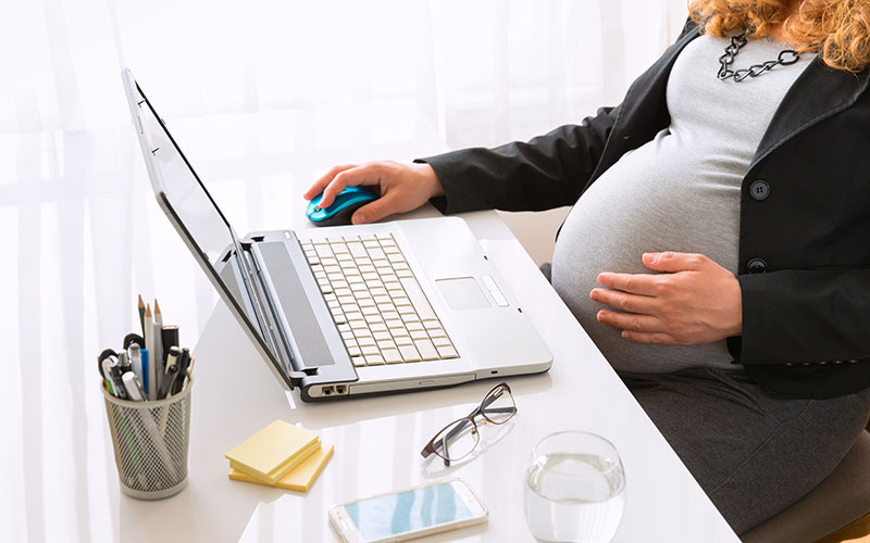 Eine schwangere Frau erledigt einen Job am Schreibtisch