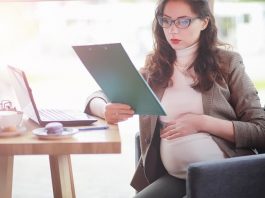 Eine schwangere Frau mit Laptop und Notizen