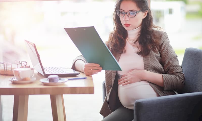 Eine schwangere Frau mit Laptop und Notizen