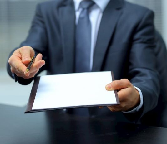Ein Mann hält Stift und Papier entgegen
