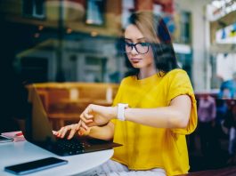 Eine Frau schaut auf die Uhr bei der Arbeit um keine Minusstunden zu machen