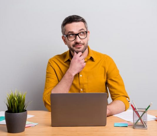Ein Mann sitzt nachdenklich vor einem Laptop und nutzt einen Gehaltsrechner