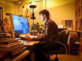 Ein Mann sitzt im Home-Office am PC und arbeitet aufgrund der Vertrauensarbeitszeit in der Nacht