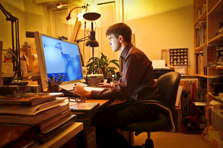 Ein Mann sitzt im Home-Office am PC und arbeitet aufgrund der Vertrauensarbeitszeit in der Nacht