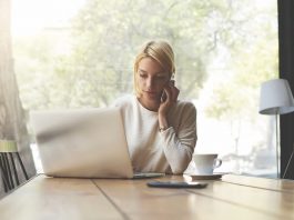 Eine Frau sitzt im Homeoffice am Laptop und telefoniert