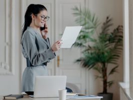 Eine junge Frau ist in ihrer Wohnung und hält ihr Ausbildungszeugnis in der Hand