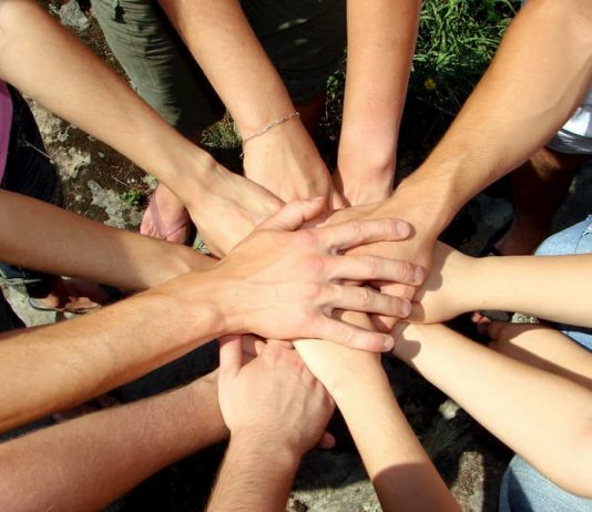 Aufeinander gelegte Hände sind ein Symbol für Teamwork