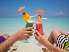 Zwei Menschen haben Erholungsurlaub und trinken Cocktails am Strand