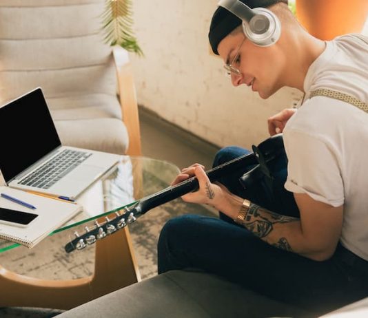 Ein Mann hat Rufbereitschaft, währenddessen kann er Zuhause Gitarre spielen