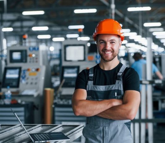 Ein glücklicher Mann in der Werkshalle mit einer hohen Mitarbeiterzufriedenheit