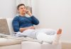 Ein Mann mit gebrochenem Bein telefoniert, er erhält Krankengeld