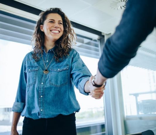 Eine Frau ist bei einem Jobinterview und begrüßt den Personaler