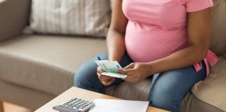 Eine Frau berechnet das Mutterschaftsgeld und hält andere Ersparnisse in der Hand