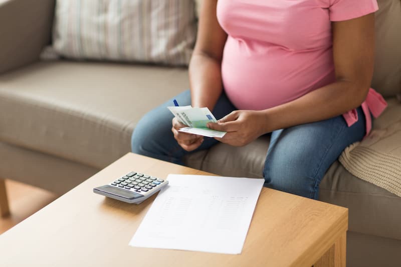 Eine Frau berechnet das Mutterschaftsgeld und hält andere Ersparnisse in der Hand