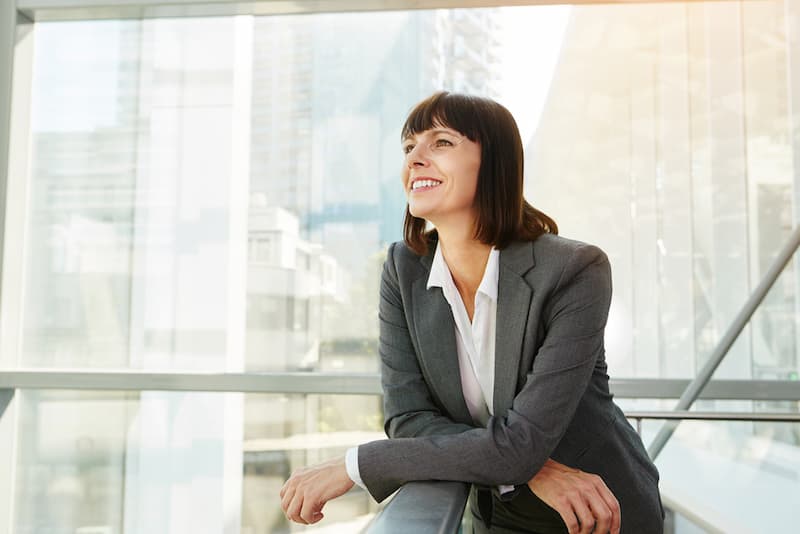 Ein Frau im Anzug steht an einer Balustrade, sie ist ein Beispiel für Female Leadership