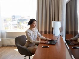 Eine Frau im Hotelzimmer schreibt an einer Reisekostenabrechnung