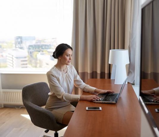 Eine Frau im Hotelzimmer schreibt an einer Reisekostenabrechnung