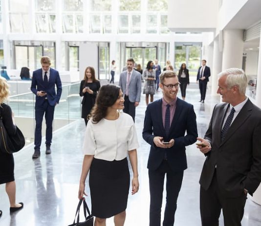 Mehrere Personen in einer Lobby eines Gebäudes, sie haben unterschiedliche Arbeitsmodelle