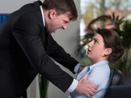 Eine Frau wird vom Chef gehalten, ein Beispiel für Gewalt am Arbeitsplatz