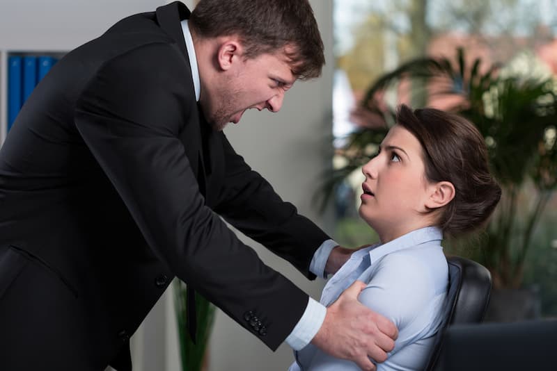 Eine Frau wird vom Chef gehalten, ein Beispiel für Gewalt am Arbeitsplatz