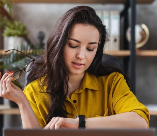 Eine Frau sieht auf die Uhr, sie kann dank dem Überstundenausgleich früher nach Hause gehen