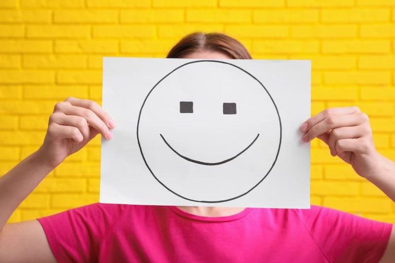 Eine Frau hält ein Papier mit einem Smiley, zu nett sein ist nicht immer gut