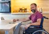 Ein Mann im Rollstuhl schreibt an einer Bewerbung mit Schwerbehinderung