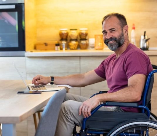 Ein Mann im Rollstuhl schreibt an einer Bewerbung mit Schwerbehinderung