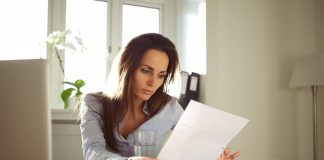Eine Frau liest ihren Arbeitsvertrag, welche Rechte hat man bei der Entfristung?