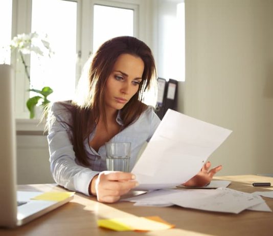 Eine Frau liest ihren Arbeitsvertrag, welche Rechte hat man bei der Entfristung?