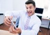 Ein Mann spielt mit seinem Smartphone auf der Arbeit, das kann eine Pflichtverletzung im Job sein