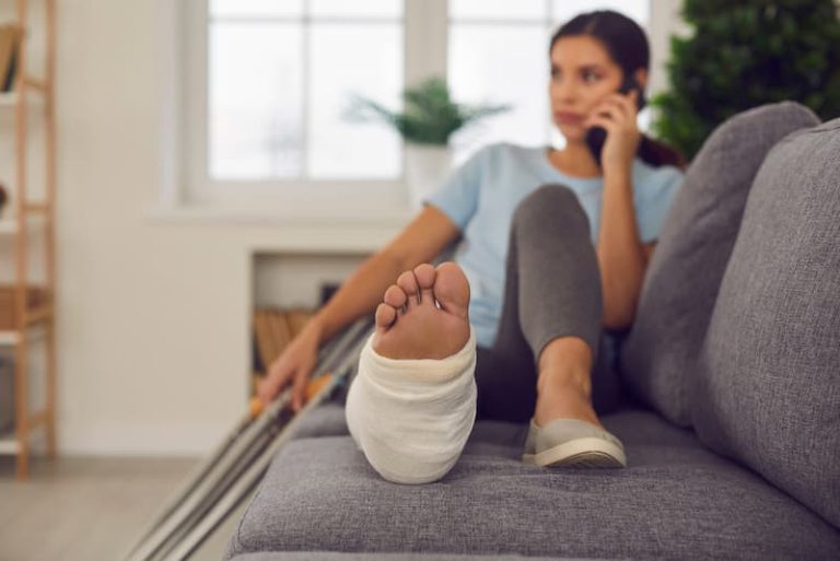 Eine junge Frau mit Gips am Bein, was passiert, wenn man in der Probezeit krank wird?