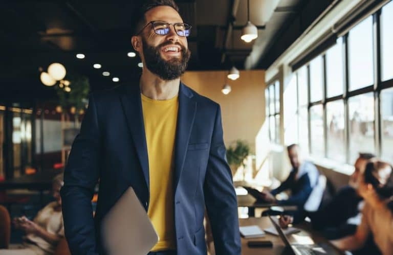 Ein Mann ist glücklich auf der Arbeit, wie gelingt Selbstverwirklichung im Job?