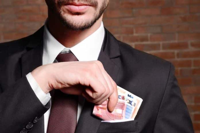 Ein Mann steckt Geldscheine in die Jackentasche, was ist Schwarzarbeit?