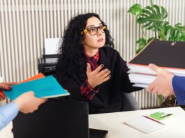 Eine Frau erhält viele Ordner gereicht, was lässt sich tun gegen ungerechte Behandlung am Arbeitsplatz?