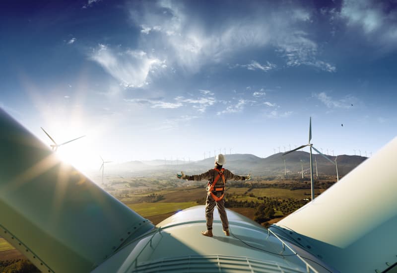 Ein Mann steht auf einer Windkraftanlage, was sind grüne Jobs?