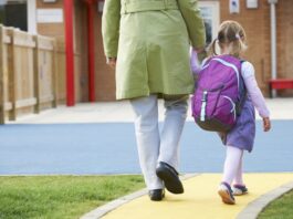 Eine Mutter bringt das Kind in den Kindergarten, was ist betriebliche Kinderbetreuung?