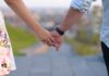 Zwei Menschen halten ihre Hände, ist eine Beziehung am Arbeitsplatz sinnvoll?