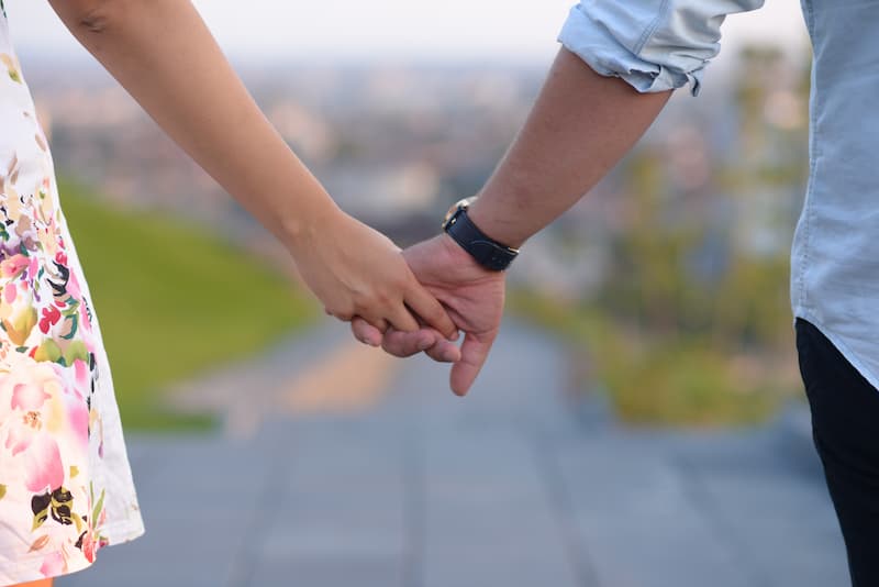 Zwei Menschen halten ihre Hände, ist eine Beziehung am Arbeitsplatz sinnvoll?