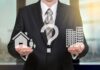 Ein Mann hält ein Haus- und ein Büro-Symbol in der Hand, sollte man Arbeit und Privates trennen?