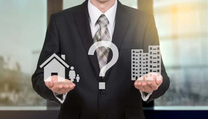 Ein Mann hält ein Haus- und ein Büro-Symbol in der Hand, sollte man Arbeit und Privates trennen?
