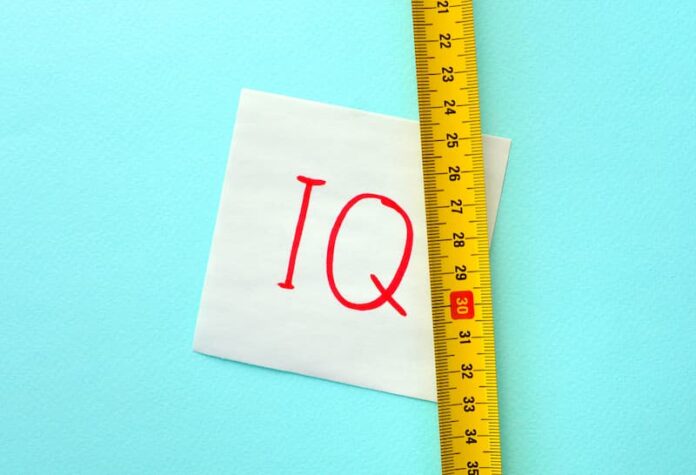 Ein Maßband neben einem Papier auf dem IQ steht, wie lässt sich der Intelligenzquotient messen?