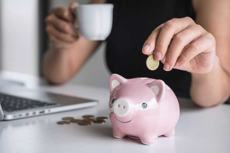 Ein Sparschwein wird befüllt, was sind gute Tipps zum Geld sparen?