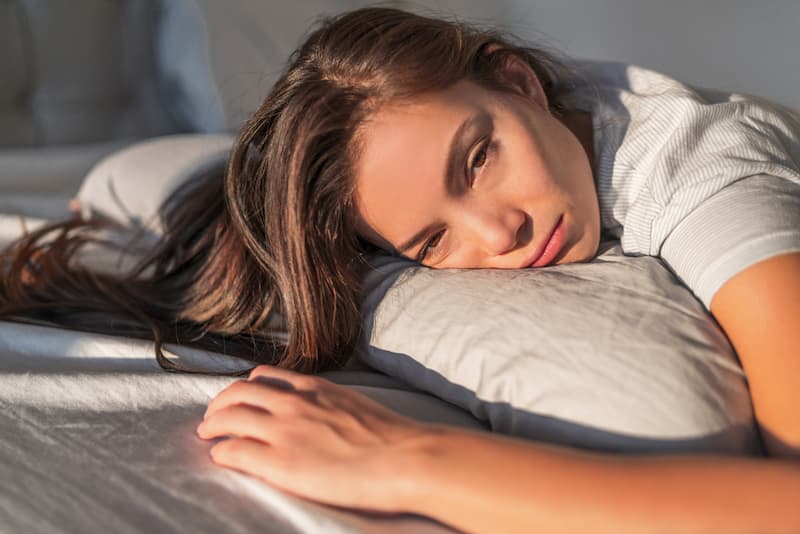Eine Frau liegt auf einem Kissen, was ist das Chronische Erschöpfungssyndrom?