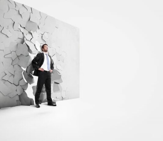 Ein Mann durchbricht eine Wand, was ist Durchsetzungsvermögen?