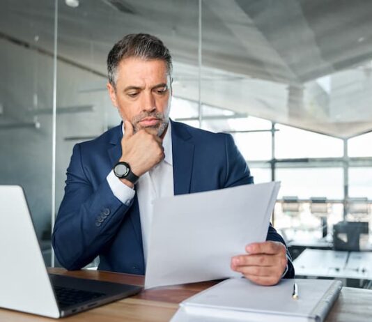 Ein Mann liest sich Unterlagen durch, was ist eine Tisax-Zertifizierung?