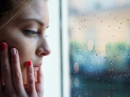 Eine Frau sitzt vor dem Fenster, was ist soziale Isolation?