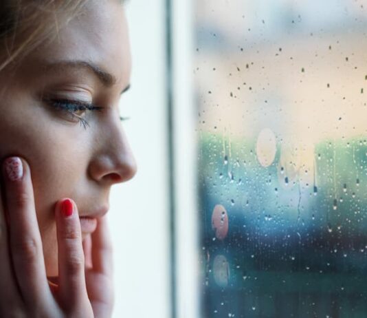Eine Frau sitzt vor dem Fenster, was ist soziale Isolation?